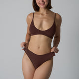 Woman wearing a brown underwear set against a plain background