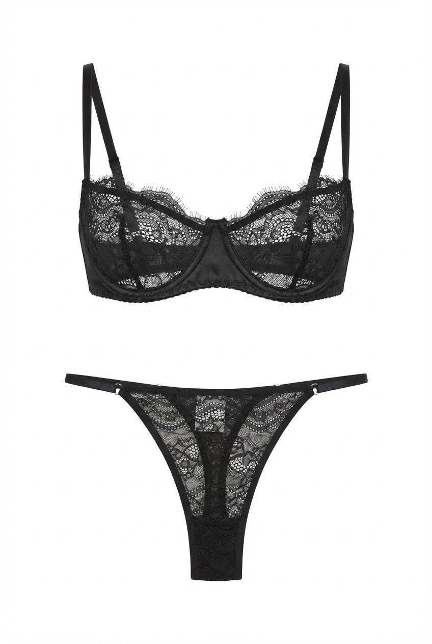 Black lace lingerie set displayed on a white background, featuring an underwired demi bra with sheer floral lace cups and matching low-rise lace thong with slim adjustable side straps.