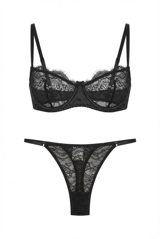Black lace lingerie set displayed on a white background, featuring an underwired demi bra with sheer floral lace cups and matching low-rise lace thong with slim adjustable side straps.