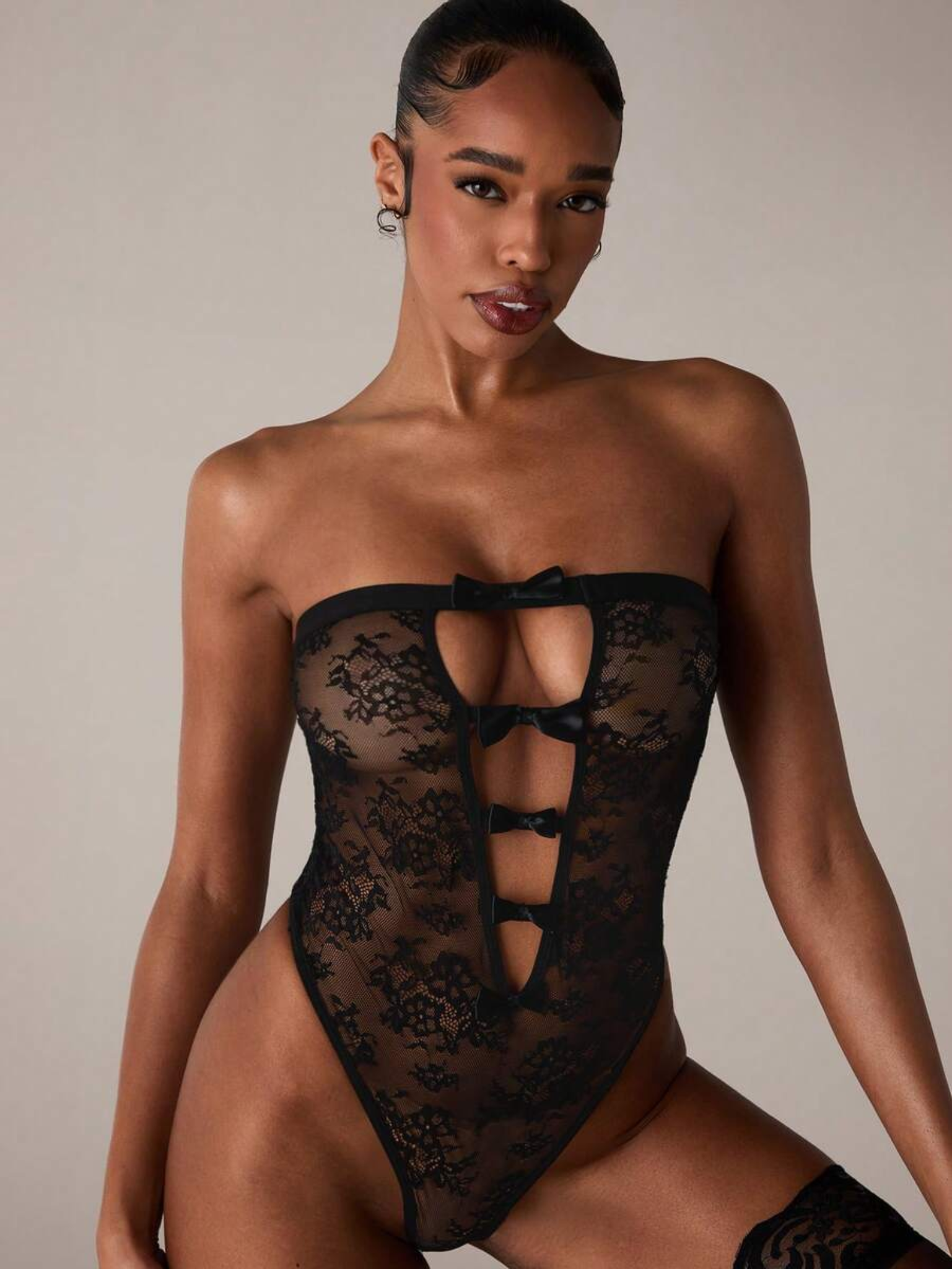 close-up of sabrina black lace bodysuit with strapless neckline, sheer floral panels and high-cut leg